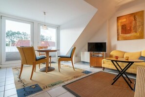 Un salon moderne comprenant un coin repas, un téléviseur et un canapé.