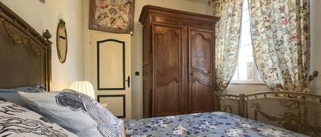 A bedroom with a bed, a wardrobe, a mirror, and a floral curtain.