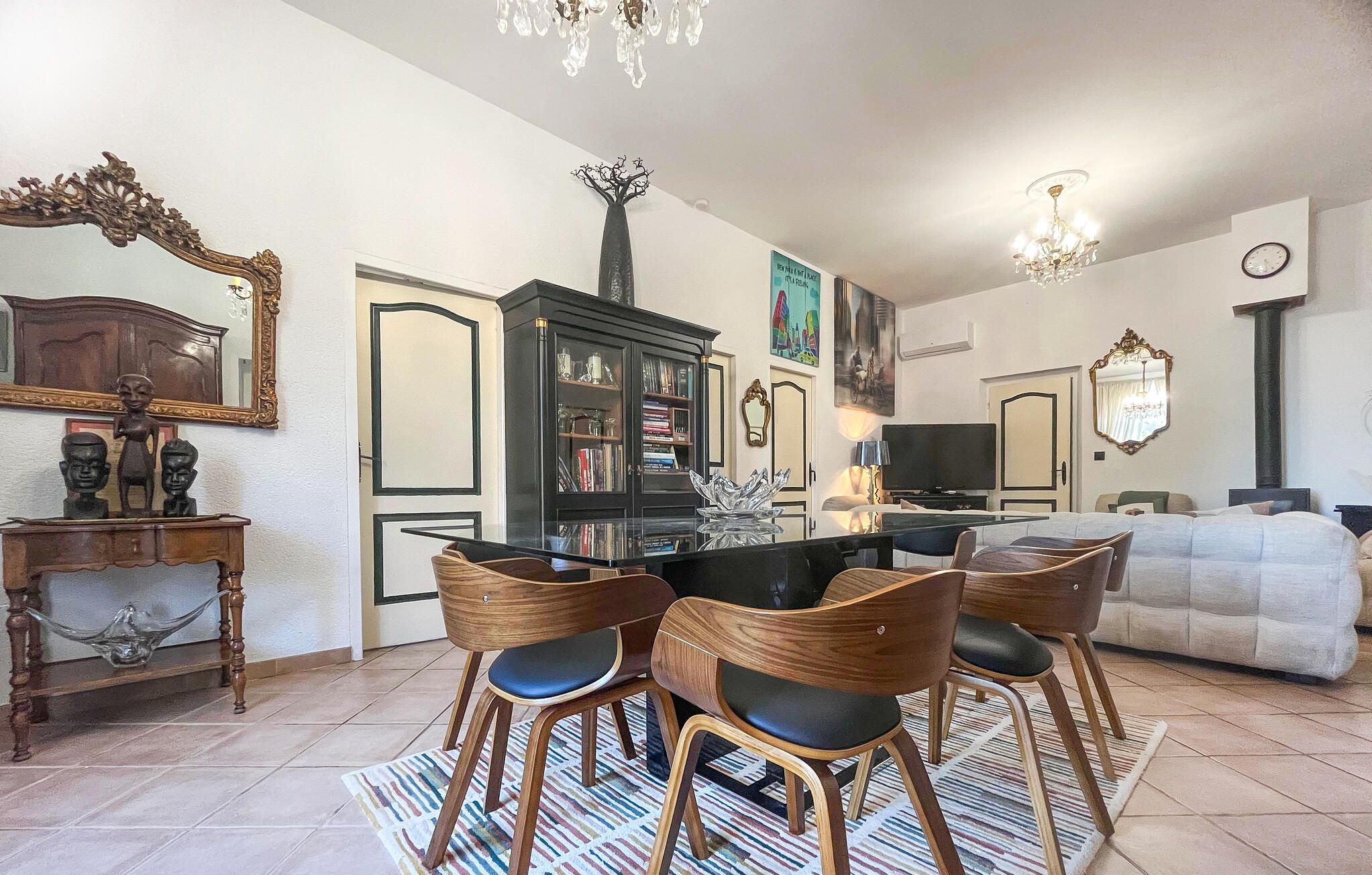 A dining area with a round table, wooden chairs, and a patterned rug.