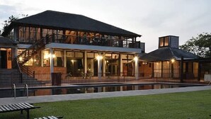 A two-story building with a pool, outdoor seating, and a staircase leading to an upper level. - Chaminuka Luxury Lodge (Lusaka)