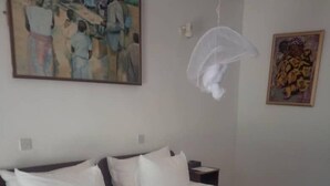 A hotel room with two beds, white linens, a painting on the wall, and a hanging mosquito net. - Chaminuka Luxury Lodge (Lusaka)