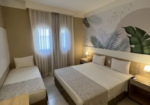 A hotel room with two beds, a large window with curtains, a wall mural, and a bedside table with a lamp. - Fildi Hotel (Sumare)