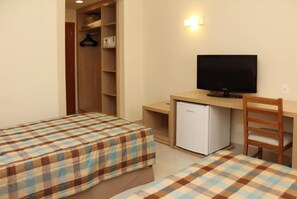 Ein Schlafzimmer mit zwei Betten, einem Schreibtisch, einem Fernseher und einem kleinen Kühlschrank.