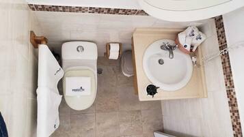 A bathroom with a toilet, bidet, sink, and mirror.