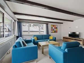 A modern living room with blue sofas, a wooden coffee table, and a TV on a wooden stand. - Seeli Appartement/Fewo,   Ferienwohnung Seeli IH by Interhome (Churwalden)
