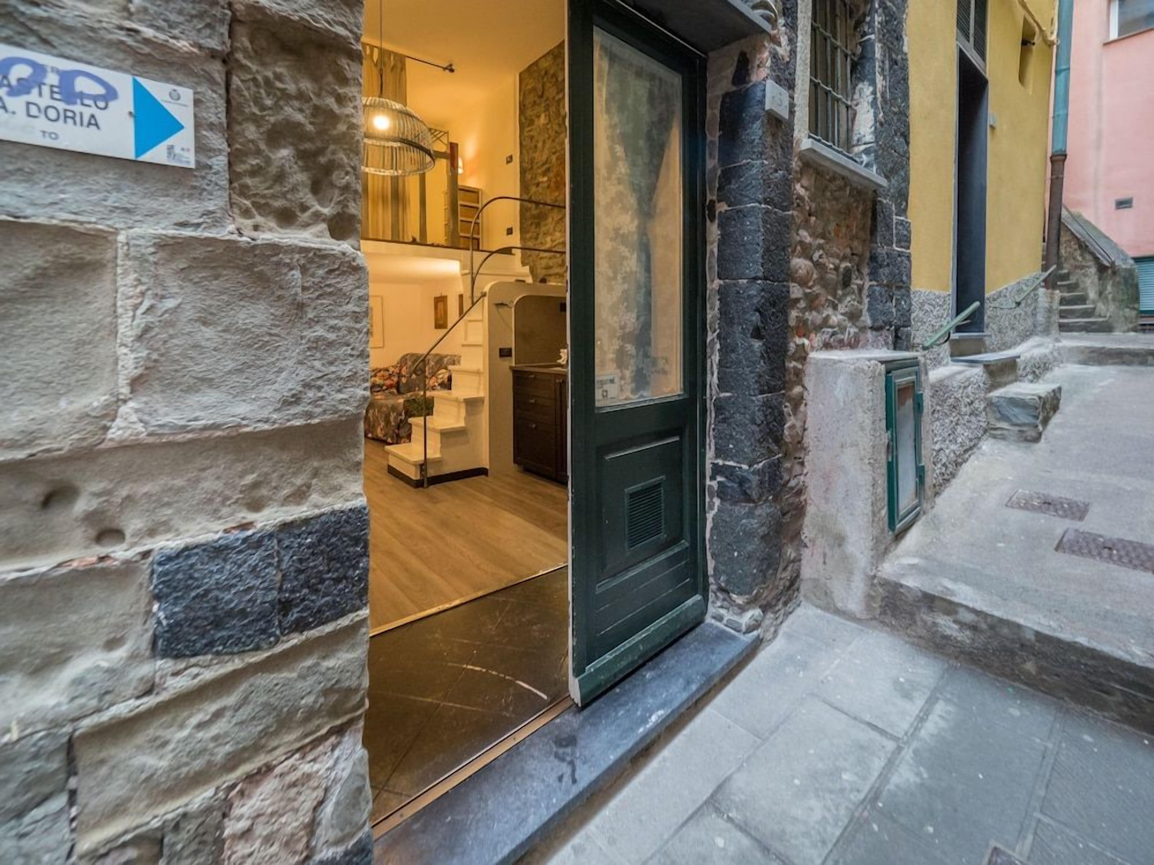 A stone facade with a door leading to a room with a wooden floor and a modern interior.