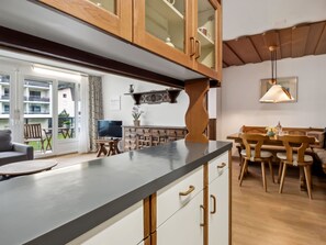 A modern kitchen with wooden cabinets, a black countertop, and a dining area with wooden chairs and a table. - Nr.63 Haus Ladina Appartement/Fewo,   Nr.63 Haus Ladina IH by Interhome (Lenzerheide)