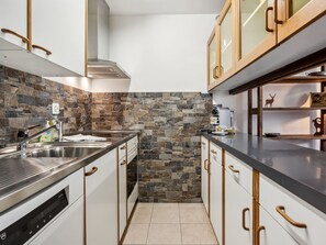 Eine moderne Küche mit einer Steinrückwand, Edelstahlgeräten und Holzschränken.