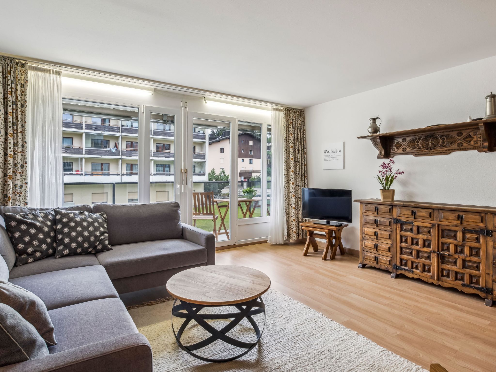 A living room with a sofa, a coffee table, a TV, and a wooden cabinet.