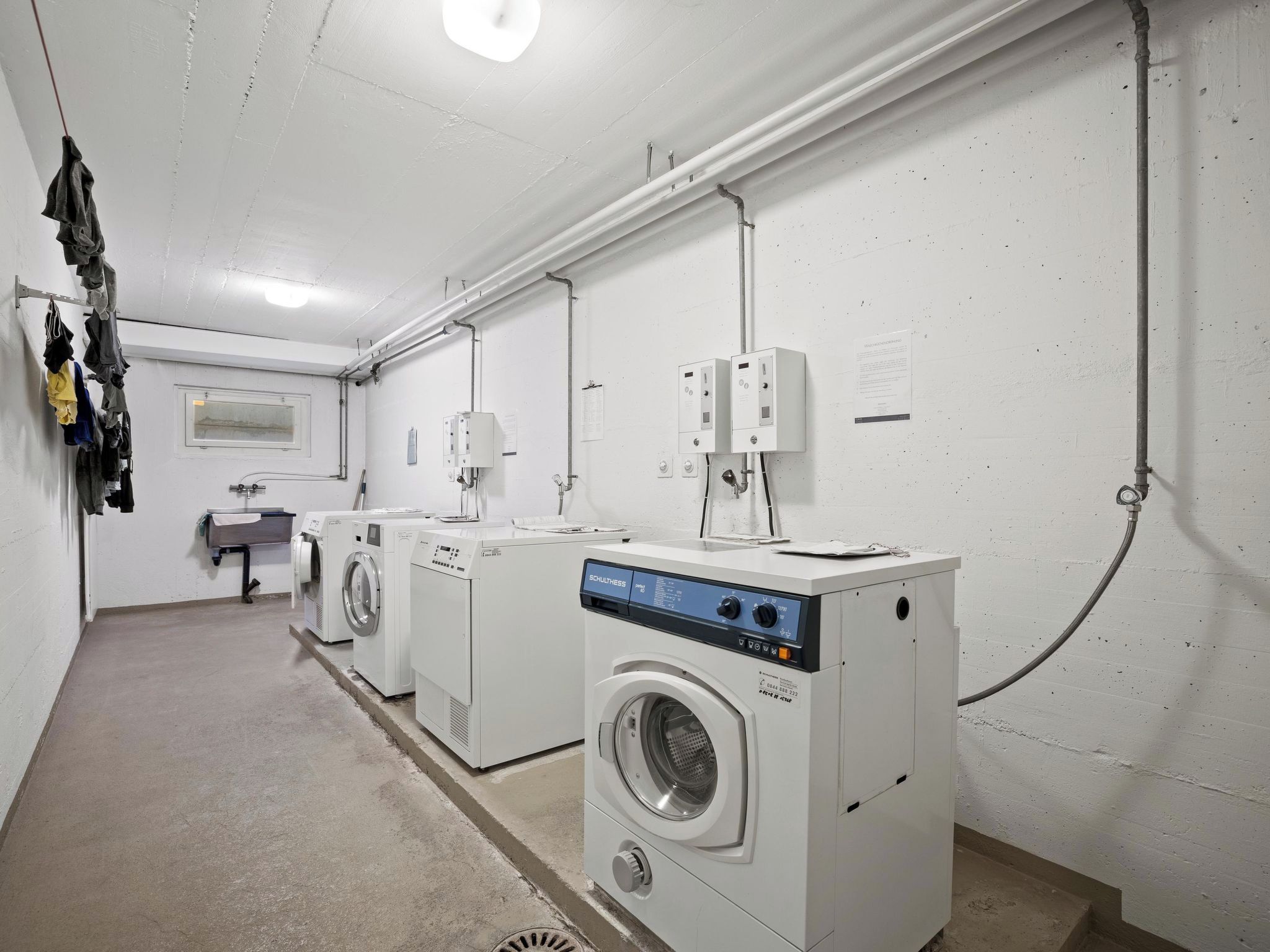 Une buanderie équipée de deux machines à laver à chargement frontal, d’un sèche-linge et d’un évier utilitaire.