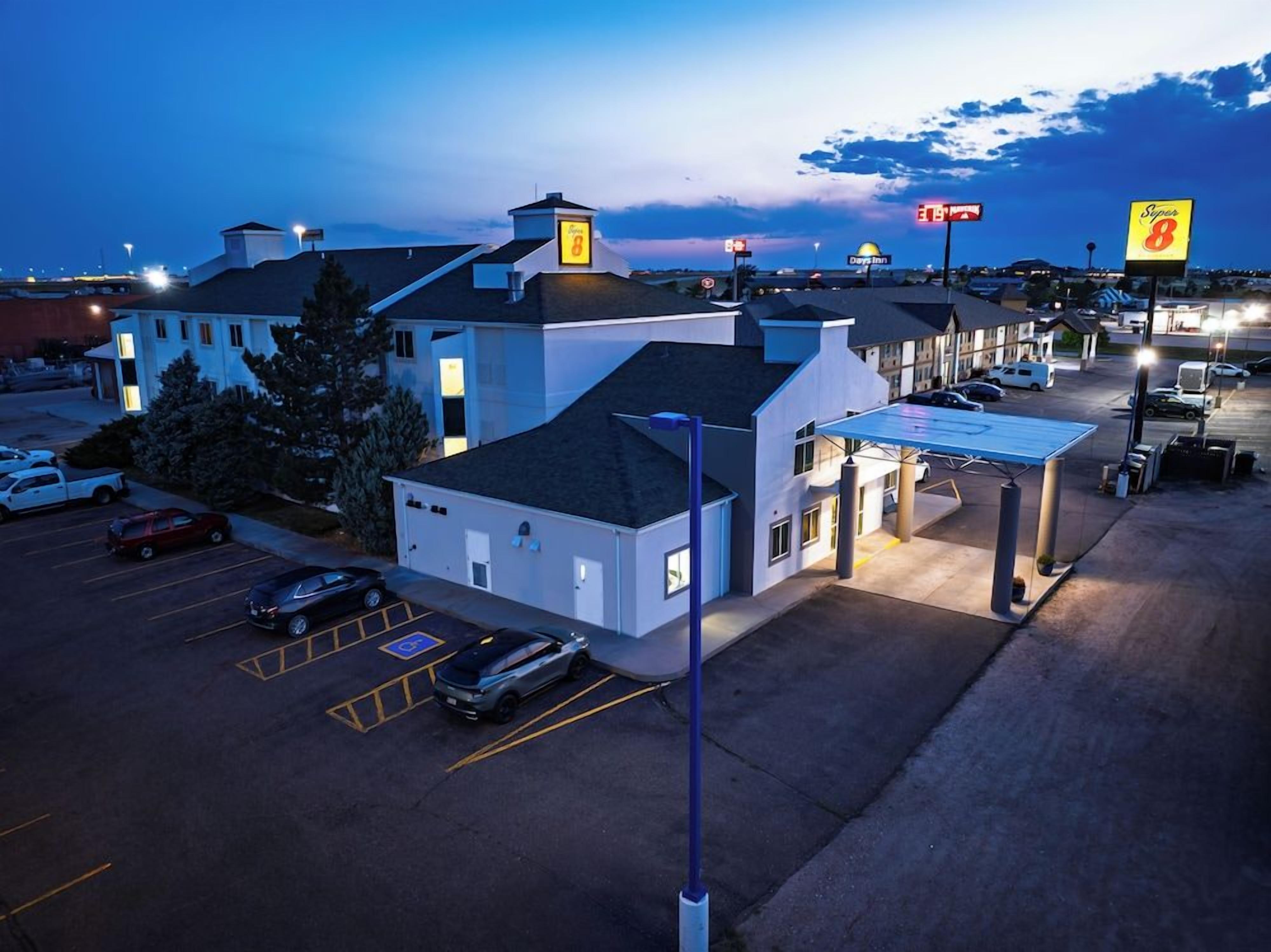 A hotel with a parking lot, a covered outdoor area, and a view of the surrounding area.
