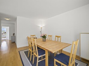 A dining area with a wooden table, six chairs, a vase with flowers, and a floor lamp. - Moser Appartement/Fewo Ferienwohnung Moser IH by Interhome (Churwalden)