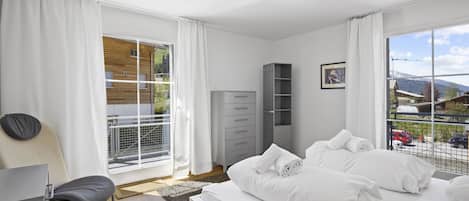 Une chambre moderne avec un grand lit, un bureau et une vue sur l’extérieur.