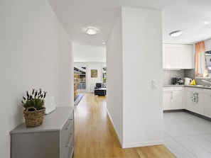A modern kitchen with white cabinets, a wooden floor, and a dining area with a black sofa. - Moser Appartement/Fewo Ferienwohnung Moser IH by Interhome (Churwalden)