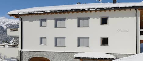 Un immeuble à plusieurs étages, avec une base en pierre et un toit recouvert de neige.