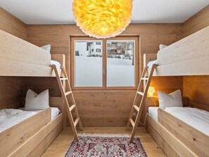 A room with two bunk beds, a window with a view of a snowy landscape, a wooden floor, and a patterned rug. - Praval Appartement/Fewo Ferienwohnung Praval IH by Interhome (Valbella)