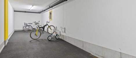 A parking garage with bicycles parked against the walls.