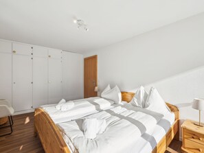 A bedroom with a wooden bed, white linens, a wooden wardrobe, and a wooden door. - Nr.06 Haus Sursilvana Appartement/Fewo,   Nr.06 Haus Sursilvana IH by Interhome (Lenzerheide)