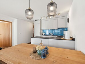 Eine moderne Küche mit weißen Schränken, einer blauen Spritzschutzleiste und einem Holztisch mit Untersetzer.