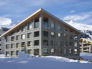 A modern building with a triangular roof, large windows, and a snow-covered ground. - Parvenda Appartement/Fewo Ferienwohnung Parvenda IH by Interhome (Lenzerheide)