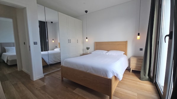 Quarto moderno com cama de madeira, closet espaçoso e um espelho grande.