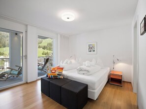 Et moderne soveværelse med en stor seng, udsigt til en balkon og et maleri på væggen.