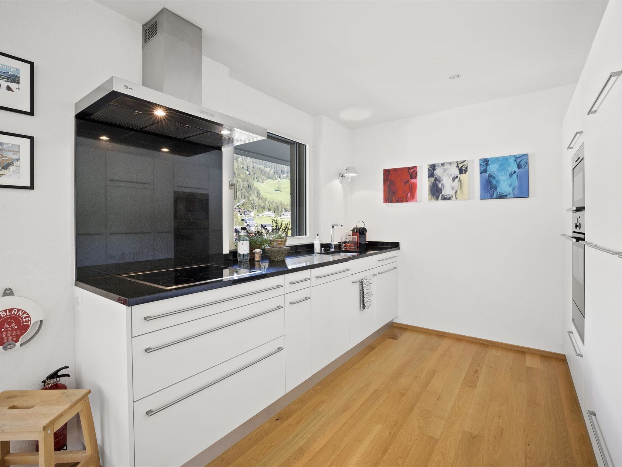 A modern kitchen with a large island, white cabinetry, and a view of the outdoors.