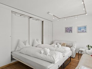 Une chambre à coucher moderne et minimaliste, avec un grand lit, une table de chevet et deux tableaux accrochés au mur.