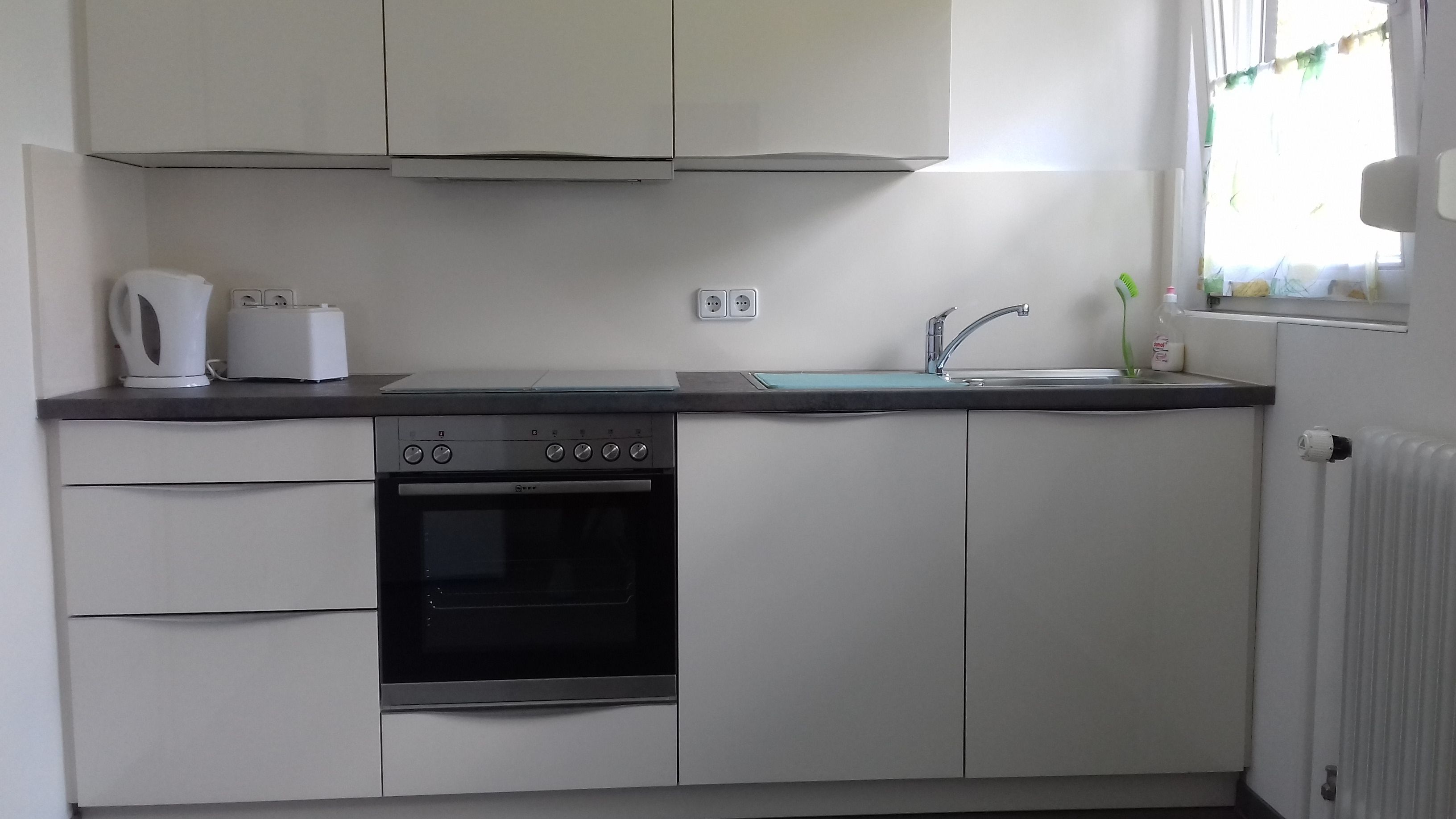 Eine kleine Küche mit integriertem Backofen, Spüle und Wasserkocher auf der Arbeitsfläche.