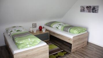 Ein kleines, gemütliches Schlafzimmer mit zwei Einzelbetten, einem Nachttisch, einer Lampe und einem kleinen Tisch.
