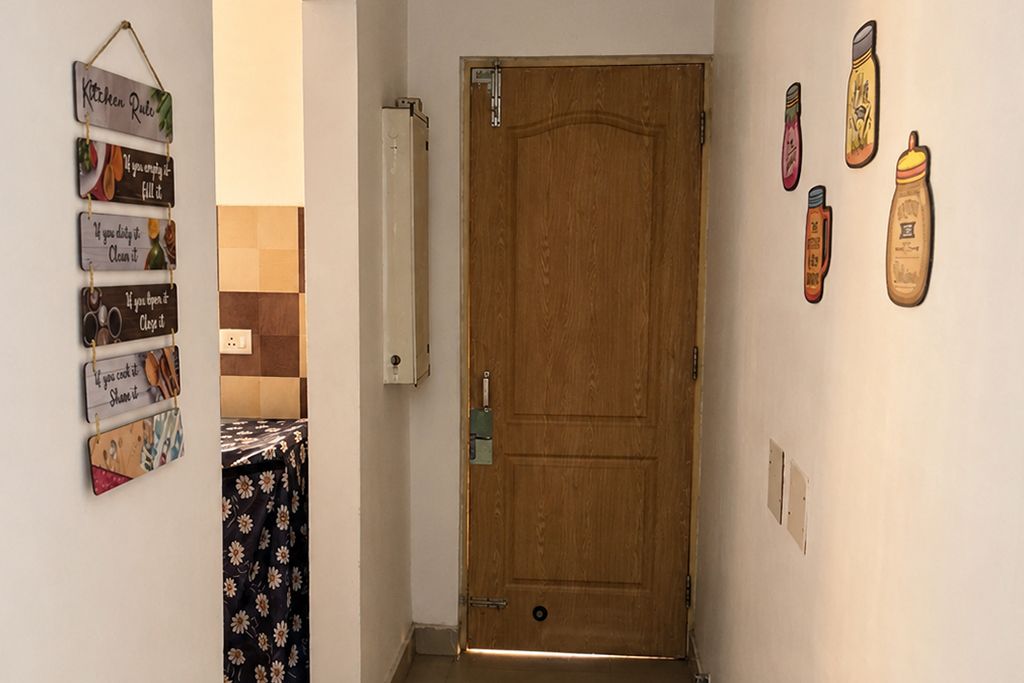 Un couloir avec une porte en bois, un luminaire fixé au mur et une série de panneaux décoratifs sur le thème de la cuisine.