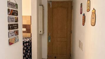 Un couloir avec une porte en bois, un luminaire fixé au mur et une série de panneaux décoratifs sur le thème de la cuisine.