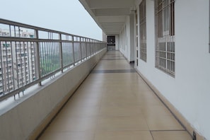 A corridor with a metal railing, tiled floor, and barred windows. - Cozy Stay Royal bnb in Tricity (Sahibzada Ajit Singh Nagar)