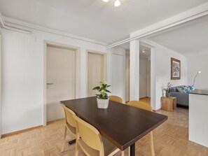 A dining area with a table, chairs, and a potted plant. There is a sofa and a small side table in the background. - Bellavista 4 Appartement/Fewo, Bad, WC, 2 Schlafräume by Interhome (Parpan)