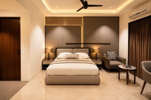 A modern bedroom with a large bed, bedside tables, a sofa, and a ceiling fan. - Fun Hotels Vadodara (Vadodara)