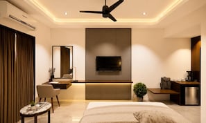 Ein modernes Schlafzimmer mit Bett, Schreibtisch, Fernseher und einer Küchenzeile.