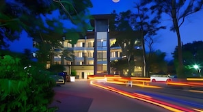 Un hôtel à plusieurs étages, doté d’un design moderne, avec une entrée imposante et une façade bien éclairée.