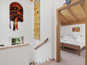 Ein Zimmer mit einem Bett, einem Kopfteil, einem an der Wand befestigten Kunstwerk, einer Treppe und einem Fenster mit Blick.