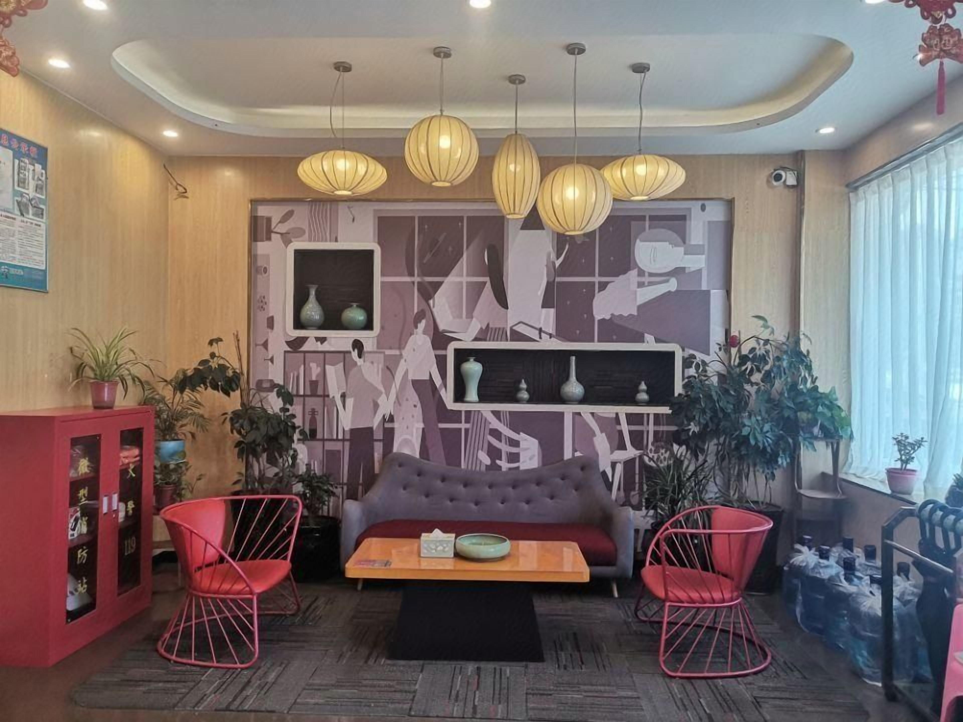 A modern living room with a sofa, two red chairs, a coffee table, and a wall with abstract art.