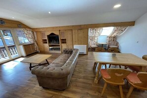 Una stanza con un divano, un tavolo da pranzo in legno, sedie, una televisione e un caminetto.