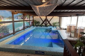 Una piscina interna con vista su un paesaggio montuoso attraverso ampie finestre.