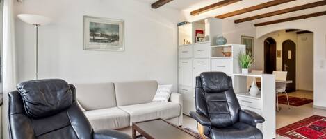 Ein modernes Wohnzimmer mit einer Couch, zwei Ledersesseln, einem Couchtisch und einem Bücherregal.