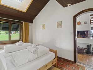 A bedroom with a wooden bed, two rolled towels, a window with curtains, and a view of the outdoors. - Al Prada 3.1.a Appartement/Fewo,   Ferienwohnung Al Prada 3.1.a IH by Interhome (Lenzerheide)