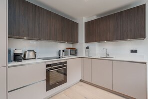 Eine moderne Küche mit dunklen Holzschränken, Edelstahlgeräten und einer weißen Arbeitsplatte.