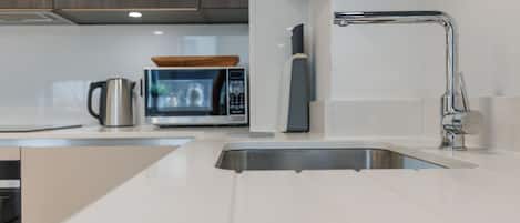 A modern kitchen with a stainless steel sink, a microwave, and a kettle.