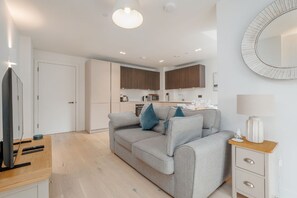 Ein modernes Wohnzimmer mit einem grauen Sofa, einem Holztisch und einem Fernseher.