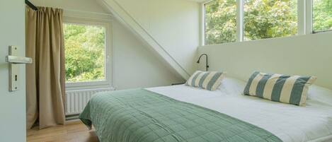 A bedroom with a bed, a window, and a door.