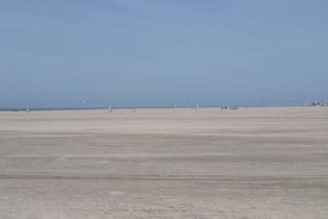 Uma praia larga e plana com céu claro.