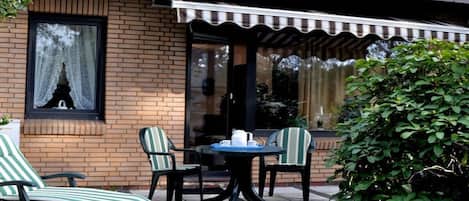 A brick building with a covered patio area featuring a table and two chairs.