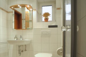 Ein Badezimmer mit Waschbecken, Spiegel, Toilette und einem Fenster mit einem Blumentopf.